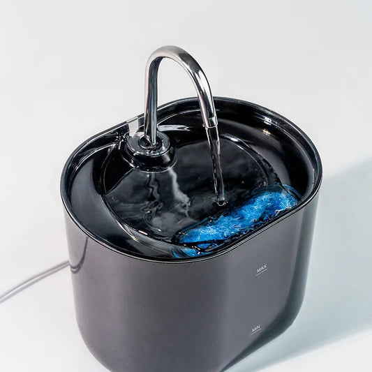 Close-up of the black fountain's top tray with water running from the curved spout over a blue filter