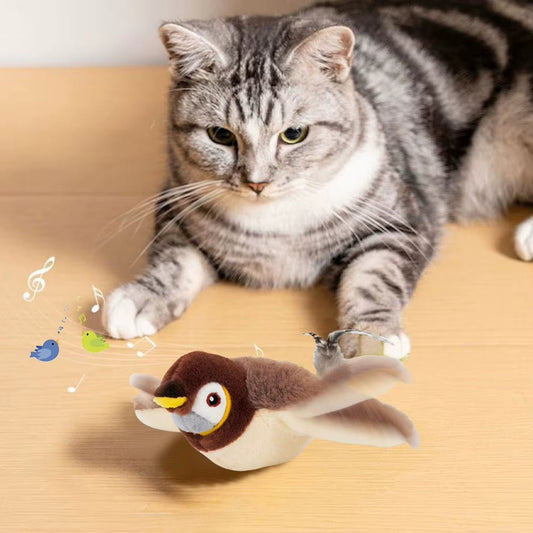 Silver tabby cat lying on a wooden floor behind the plush sparrow toy with its wings spread