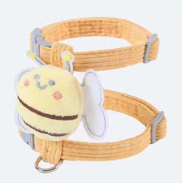 Close-up of the mustard corduroy strap harness with a plush yellow bee with white wings, grey sliders and a metal D-ring