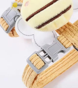 Close-up of a grey side-release buckle and slider on the corduroy harness, beneath the plush bee