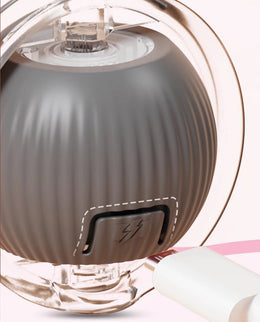 Close-up of the rolling ball in its clear frame, with the charging port flap open and a USB cable plugged in
