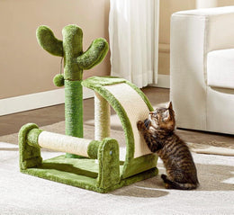 Tabby kitten standing up to scratch the curved sisal board of a green cactus cat scratcher on a rug, beside a cream armchair