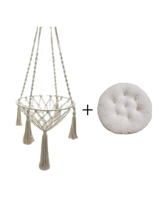 Cream knotted rope cat hammock with tassels, next to a round white fluffy cushion