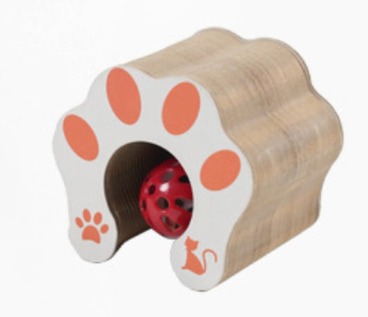 Folded cardboard accordion cat scratcher with white paw-print end caps around a red bell ball