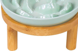 Side view of the pale green plate seated in the round bamboo stand, showing the stand's ring and wooden legs