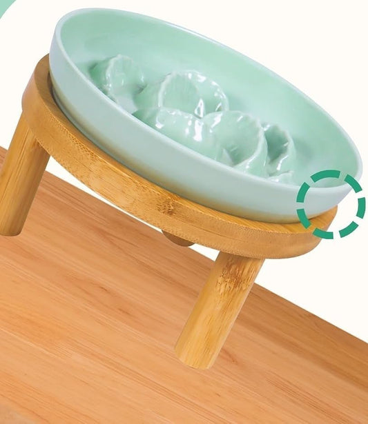 Pale green plate with dumpling-shaped ridges sitting in a round bamboo stand on wooden legs, on a wooden surface