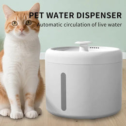Ginger and white cat sitting beside a round white water fountain with a small top spout and a side level window