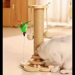 White cat nosing the balls in the wooden ball track at the foot of a rope-wrapped scratching post with two hanging rope balls and a feather teaser on a spring